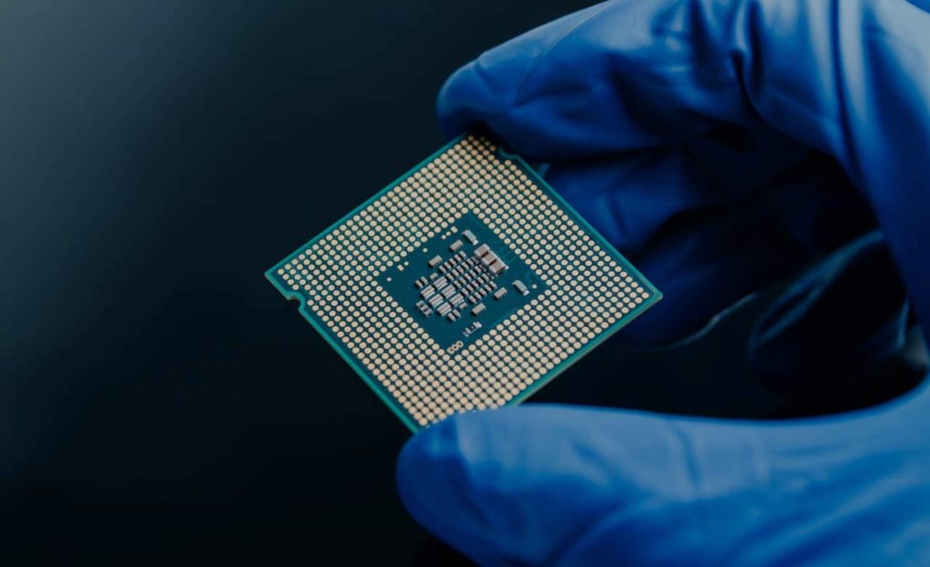 Employee holding a semiconductor while wearing a blue glove.