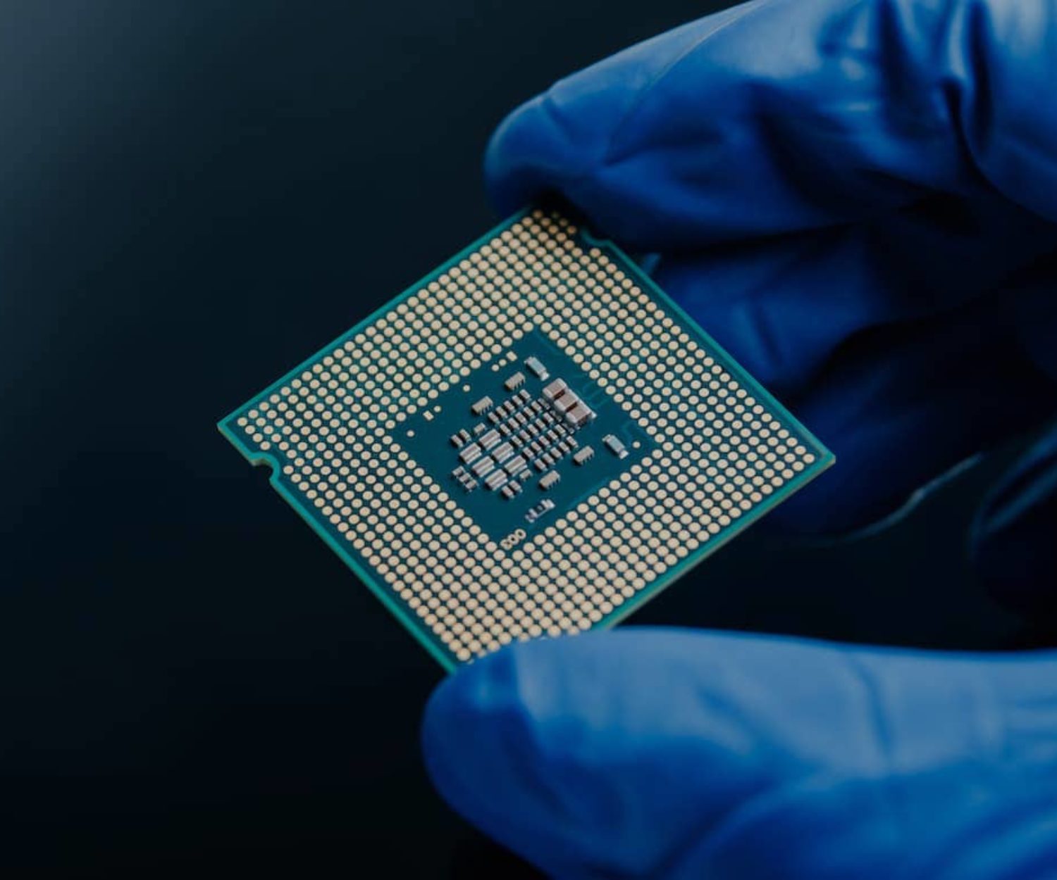 Employee holding a semiconductor while wearing a blue glove.