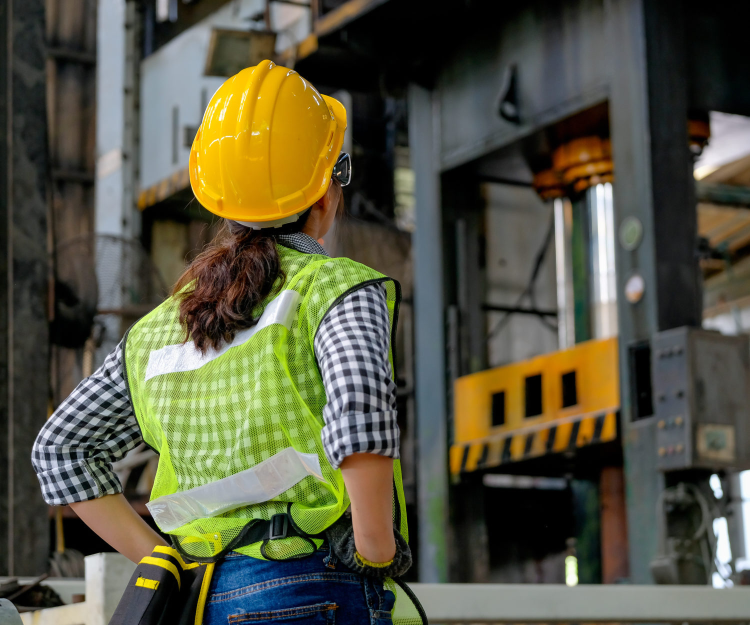 Back of factory engineer or technician worker woman stand and look in front of machine in factory workplace. Concept of good system and manager support for better industrial business.