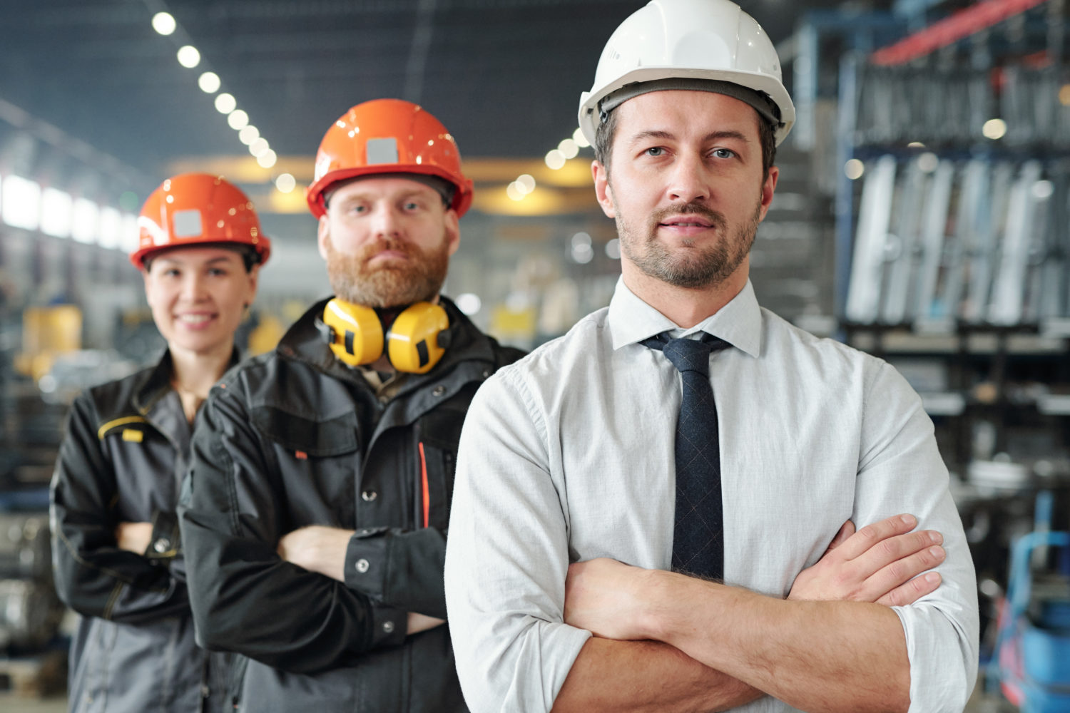 Confident leaders of manufacturing production plant standing with crossed arms in row at factory