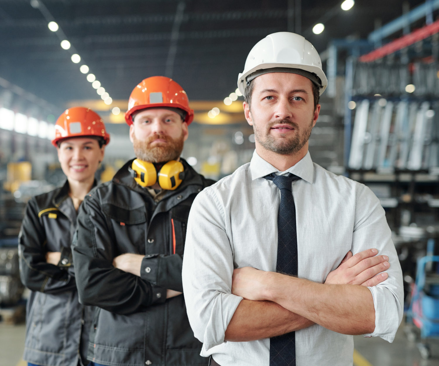 Confident leaders of manufacturing production plant standing with crossed arms in row at factory